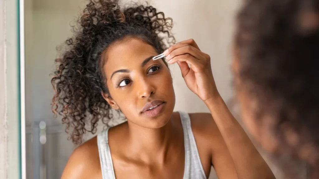 Woman plucking her hair using tweezers